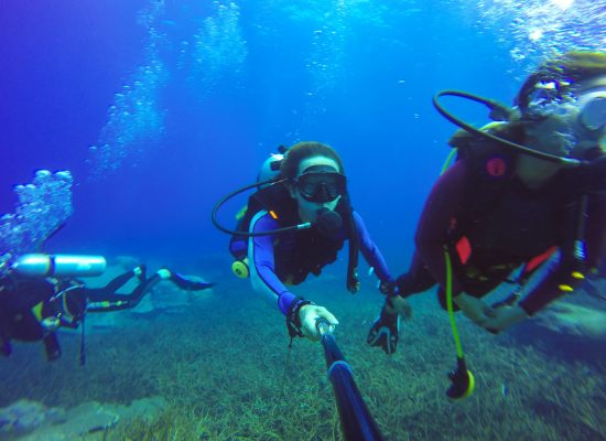 Underwater couple scuba diving selfie shot with selfie stick. Deep blue sea. Wide angle shot.